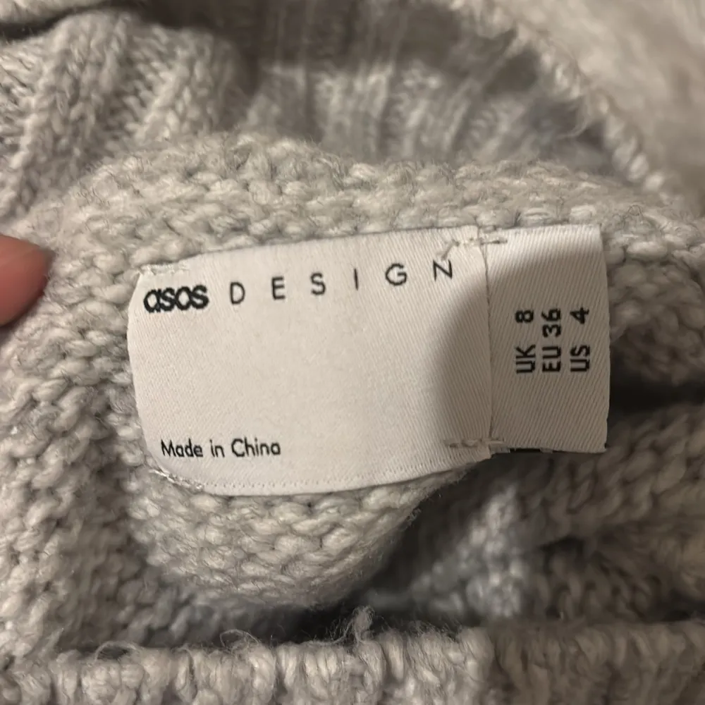 Mysig grå stickad polotröja från ASOS DESIGN. Perfekt för kyliga dagar med sin höga krage och långa ärmar. Tröjan har en avslappnad passform och är tillverkad i ett mjukt material som håller dig varm och bekväm.. Neuletakit & Villapaidat.