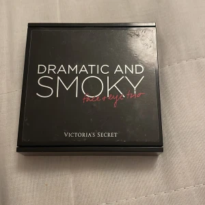 Dramatic and Smoky Face & Eye Trio - Snygg palett från Victoria's Secret med ögonskugga och bronzer. Perfekt för en dramatisk och rökig look. Innehåller två ögonskuggor i lila och rosa nyanser samt en bronzer. Kompakt design med inbyggd spegel.