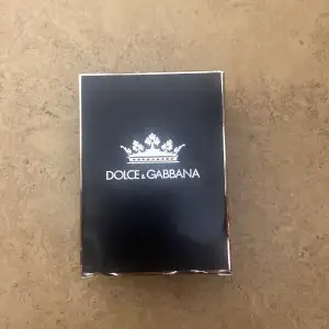 Elegant parfym från Dolce & Gabbana i en stilren svart förpackning med silverdetaljer. Förpackningen har en kunglig krona som pryder framsidan, vilket ger en lyxig känsla. Perfekt för den som söker en sofistikerad doftupplevelse.