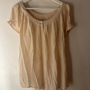 Blus Saint Tropez - Söt och fin topp i ljus beige färg med volangärmar och en knapp i mitten framtill. Toppen har en lätt, luftig känsla och är perfekt för varma dagar. Lite smått smått nopprig, se bild 3, men syns knappt. Storlek L