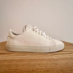 Vita sneakers från Axel Arigato - Snygga vita sneakers från Axel Arigato i minimalistisk design. Skorna har en stilren look med snörning och är tillverkade i skinn. Perfekta för en stilren vardagslook.