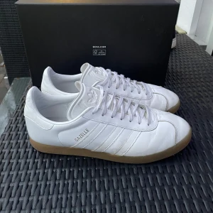 Adidas Gazelle - Säljer mina vita gazelle skor, skicket är 8/10 och de har använts sparsamt 🙏 Passar perfekt som slitskor och går att kombinera med många outfits! Hör av er vid andra frågor ✅