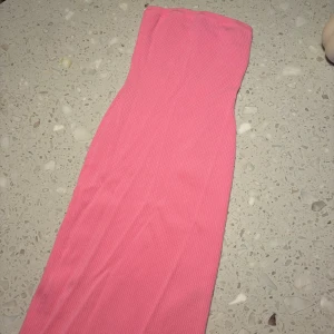 Rosa axelbandslös klänning från NA-KD - Snygg rosa axelbandslös kort klänning från NA-KD i ribbat material. Perfekt för en somrig look med sin figurnära passform och stilrena design. 