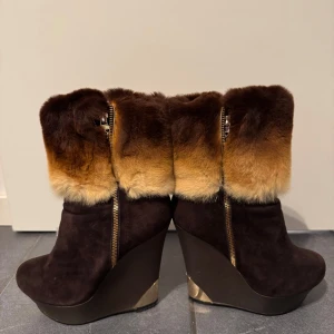 Bruna kilklackade boots med pälsdetalj strö.39 14 cm hög - Snygga bruna boots med kilklack och dragkedja. De har en lyxig pälsdetalj i brunt och beige som ger extra värme och stil. Perfekta för kyligare dagar.