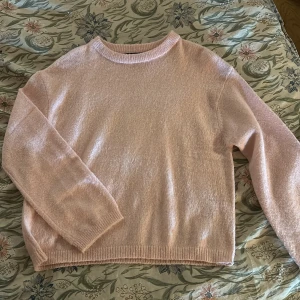 Ljusrosa stickad tröja - Mysig ljusrosa stickad tröja med rund hals och långa ärmar. Perfekt för kyliga dagar och ger en mjuk och bekväm känsla. Passar bra till både jeans och kjol.
