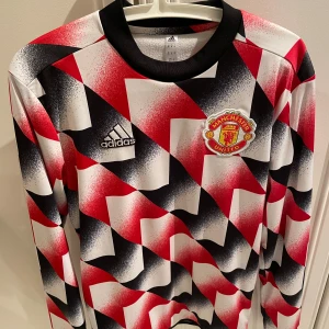 Manchester United tröja från Adidas - Säljer en cool Manchester United tröja från Adidas i storlek XS. Den har ett unikt mönster i rött, svart och vitt med klubbens emblem på bröstet. Tröjan är långärmad och i mycket bra skick. Perfekt för fans som vill sticka ut. Den har ett jätte bekvämt och varmt material på insidan. Pris kan diskuteras vid snabb affär. 