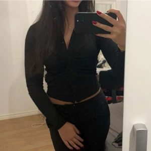 Svart croppad kofta - Säljer en snygg svart croppad skjorta med långa ärmar. Perfekt för både vardag och fest! Den har en stilren design och är superbekväm att ha på sig. Passar perfekt till höst- och vinteroutfits 🖤