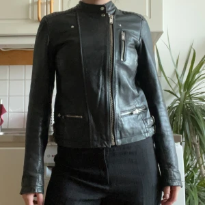 Svart skinnjacka - Snygg svart bikerskinnjacka med dragkedja och flera fickor. 100% läder, och passar XS-S