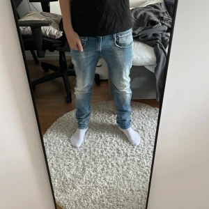 Blå jeans från Replay - Säljer ett par snygga ljusblå jeans från Replay, modell Anbass. De har en normal passform och är perfekta för både vardag och fest. Jeansen har en klassisk femficksdesign och är i mycket bra skick. Perfekta för dig som vill ha en stilren look!