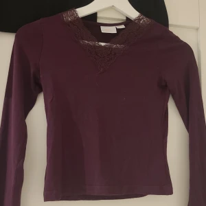 Vinröd långärmad topp med spetsdetalj - Säljer en snygg vinröd topp med lång ärm och v-ringad spetsdetalj från gina young. ❤️Perfekt för höst och vinter, och funkar både till vardags och fest. Toppen är i bra skick och har ett mjukt material🙌 Stl 134/140