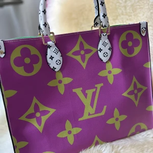 Färgglad handväska med monogram LV - Säljer en supercool handväska med ett färgglatt monogrammönster. Väskan har en mix av lila, grönt och gult med vita handtag. Insidan är ljusgul och har en praktisk ficka. Perfekt för att liva upp vilken outfit som helst!