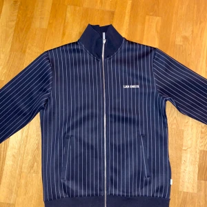 Mörkblå randig zip tröja från Les Deux - Snygg mörkblå tröja från Les Deux. Köpte den i somras för 1300kr, knappt använd. Hör av er vid frågor 