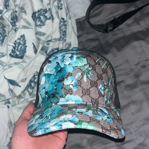 Blommig keps med blå och gröna nyanser - Kom dm för mer information 