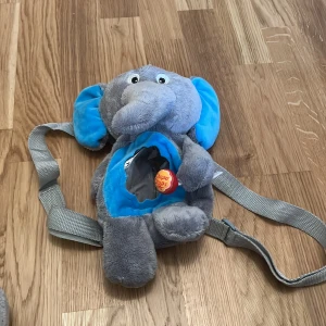 Grå elefant ryggsäck från Chupa Chups - Söt och mjuk grå ryggsäck i form av en elefant från Chupa Chups. Ryggsäcken har justerbara axelremmar och en dragkedja på baksidan för förvaring. Perfekt för barn som älskar djur och vill ha en unik väska.