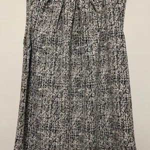 Svartvit-mönstrad ärmlös blus från Stockholm - En blus i trikå med abstrakt mönster i svartvit från Stockholm. Trikåblusen har en rund hals och knäppning i nacken. Perfekt för en stilren look.