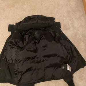 Canada goose jacka black label - En canada goose jacka black label med lite skador på, syns på dragkedjan och även på ena fickan, annars precis som den ska, därför säljs lite billigare, är problem som går att fixa.