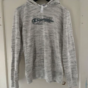 Gråmelerad hoodie från Champion - Säljer en snygg gråmelerad hoodie från Champion i storlek medium. Den har ett coolt tryck på framsidan och är perfekt för både chill och aktivitet. Materialet är mjukt och bekvämt, och den har långa ärmar och en klassisk huva. Perfekt för höst och vår!