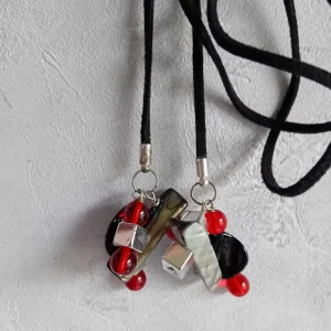 Handgjort halsband  - Handgjort halsband med svart imiterat mockaband på 1 meter samt röda, svarta och silvriga pärlor. Kan knytas på olika sätt