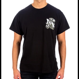 Svart t-shirt med ormmotiv från Amiri - Säljer en svart t-shirt från Amiri med ett coolt ormmotiv. T-shirten har korta ärmar och en normal passform. Perfekt för en avslappnad stil eller en utekväll. Ormen är tryckt både fram och bak, vilket ger en unik look.