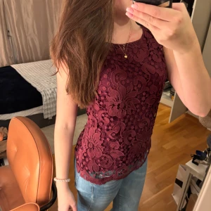 Vinröd spetslinne - Säljer ett supervackert vinrött spetslinne. Det är ärmlöst och har ett fint blommigt mönster. Perfekt för en festlig kväll eller en somrig dag. Linnet är i nyskick och passar perfekt till jeans eller kjol. Hör av dig vid intresse!