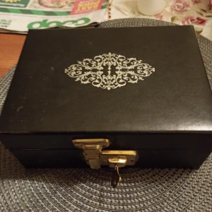 Smyckeskrin svart mönstrad med nyckel låsbart. - Fint gammalt smyckeskrin svart mönstrad med nyckel låsbart. Fint skick.