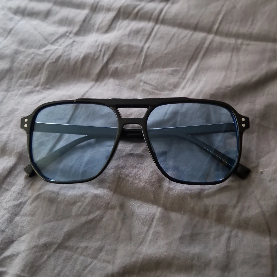 Solglasögonen ljusblått glas och svarta bågar  - 90