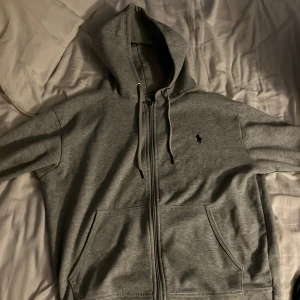 Polo Ralph lauren hel zip - Denna är i riktigt bra skick bara använt lite grann, den ser jätteriktig ut förutom ”Madde in china” men på utsidan är den helt som den riktiga. Grå hel zip i S.