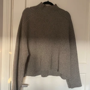 Grå ribbad tröja från H&M - Säljer en supermysig grå ribbad tröja från H&M. Den är perfekt för kyliga dagar med sin höga krage och långa ärmar. Tröjan har en loose passform som gör den extra bekväm att bära. Perfekt för både höst och vinter!