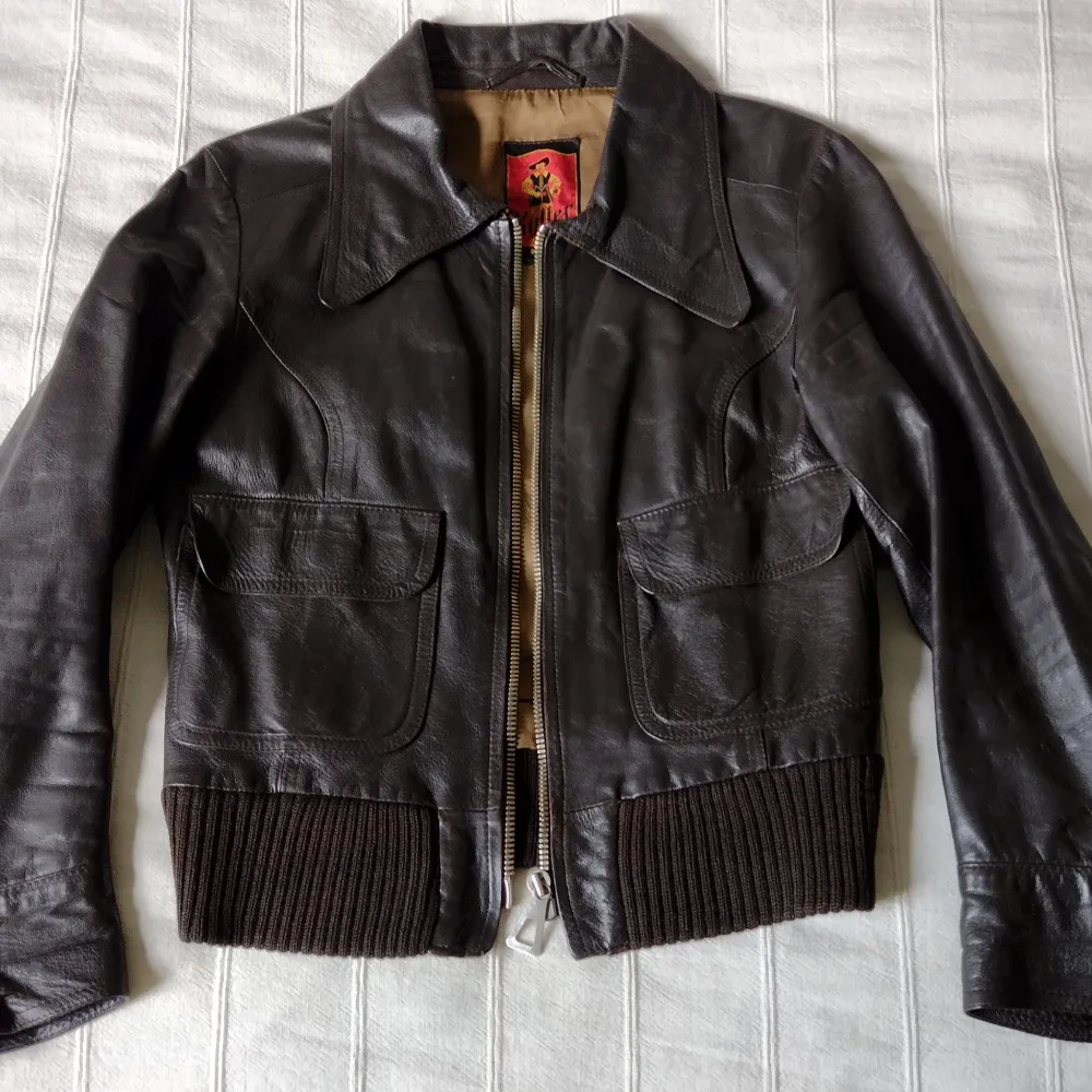 Vintage kort brun jacka i skinn i en skitsnygg modell från Kyller. Storlek 38 men jag skulle säga att den passar bäst till de som har storlek XS/S. Några små märken i lädret, lagningar i fodertyget vid armhålorna och en knapp på ena ärmen saknas. . Takit.