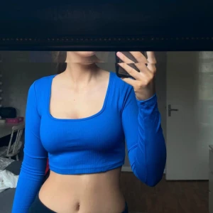 Blå ribbad croppad topp - Säljer en snygg blå ribbad topp med långärmad design. Den är croppad och passar perfekt för både vardag och fest. 
