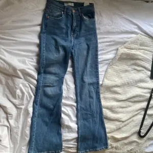 Säljer ett par snygga blå flare jeans från Bershka i storlek 36. De är tillverkade i denim och är *normal* i midjan