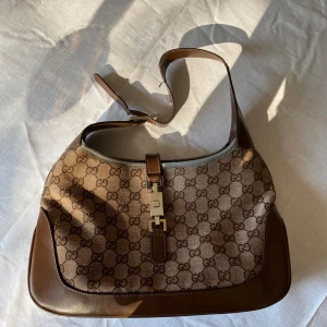 Gucci Jackie - Så fin Jackie väska från Gucci i brunt med silverdetaljer. Sliten i lädret men annars superfint skick. Köpt på plick och kan inte garantera äkthet- därav priset.