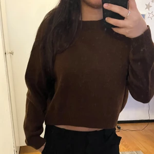 Brun croppad stickad tröja - Säljer en brun croppad stickad tröja.Tröjan har en enkel design som gör den lätt att matcha med andra plagg. Knappt använd.