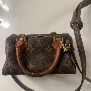 Nano Speedy Louis Vuitton - Säljer min underbara Louis Vuitton Nano Speedy som är en eftertraktad modell. Väskan köptes från Vestiaire Collective för 12 000 kr och är en äkta vintagepärla. Dock var låset redan trasigt vid köp, och även om väskan går att öppna och stänga som vanligt, har ett hål vid låset uppstått. Det går att återställa den till sitt ursprungliga skick genom att byta ut låset. Trots detta är väskan fortfarande i fint skick & fullt användbar som den är. Kommer med avtagbart axelband som enkelt kan sättas på