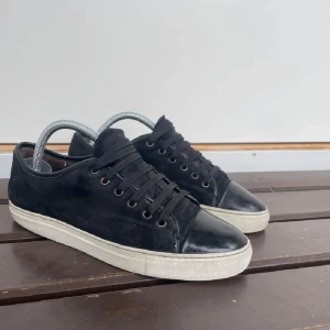 Svarta sneakers från Lanvin - Snygga svarta sneakers från Lanvin med snörning och vit sula. Perfekta för en stilren look. Storlek 41-42