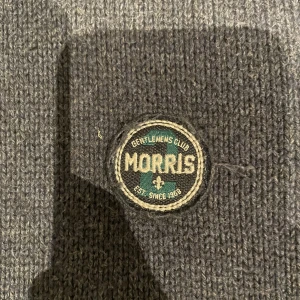 Morris crewneck  - Säljer en stilren grå stickad tröja från Morris med ett emblem på bröstet.  Tröjan har långa ärmar med ribbstickade muddar. Perfekt för kyliga dagar. Denna Morris tröjan är sällsynt. Storleken är M/L. (Nyprsis 1899 säljer för 399)