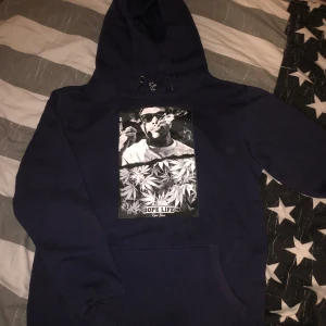 Svart hoodie med tryck - Cool svart hoodie med ett stort tryck på framsidan som visar en person med solglasögon och texten 'Dope Life'. Perfekt för en avslappnad stil.