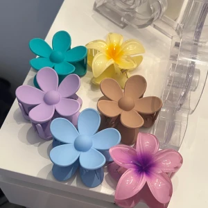 Färgglada hårklämmor i blomform - Säljer ett set med sex färgglada hårklämmor i form av blommor. Klämmorna kommer i färgerna turkos, gul, lila, brun, ljusblå och rosa. Perfekta för att ge en färgglad touch till din frisyr!