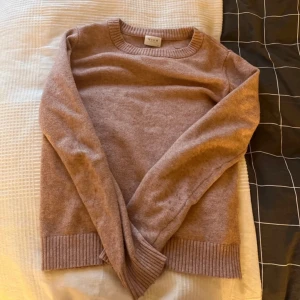 Rosa stickad tröja från Vila - Mysig rosa/beige stickad tröja från Vila med rund hals och ribbade muddar. Perfekt för kyliga dagar.