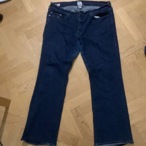 Mörkblå jeans från True Religion - Säljer ett par mörkblå jeans från True Religion med klassisk broderad ficka och bootcut-stil. Perfekta för en avslappnad look. Märkeslappen på baksidan ger en extra touch av stil.