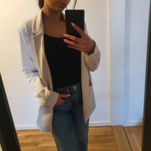 Beige kavaj  - Knappt använd! Säljer en elegant cremevit oversized kavaj i stl. S men kan även användas som storlek M med en klassisk design och två framfickor. Perfekt för en stilren look.