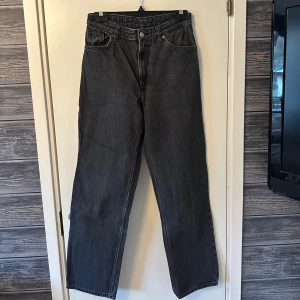 Svarta jeans med raka ben - Snygga svarta jeans med raka ben och klassisk femficksdesign. De har en hög midja och stängs med dragkedja och knapp. Har blivit lite urtvättade.