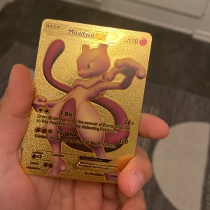 Gyllene Mewtwo EX Pokémonkort - Unikt gyllene Mewtwo EX Pokémonkort med en glänsande yta. Kortet har detaljerade illustrationer av Mewtwo och text om dess attacker, X Ball och Psydrive. Perfekt för samlare eller Pokémon-fans som vill ha något speciellt i sin samling.