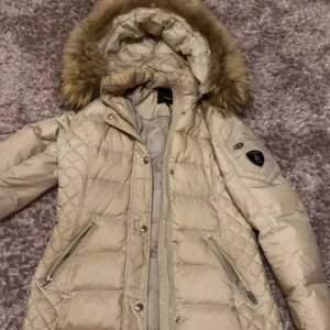 Rock and blue jacka - Pris kan diskuteras. Säljer en snygg beige rock and blue dunjacka med fluffig päls. Perfekt för kalla vinterdagar. Jackan har en dragkedja och knappar för extra värme. Den är långärmad och ser riktigt mysig ut. Passar perfekt för vinterns alla äventyr! ❄️bra skick!!!