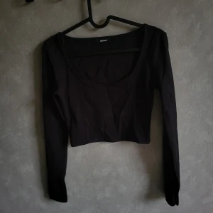 Svart croppad topp från Bik Bok - Snygg svart croppad topp från Bik Bok med långa ärmar. Perfekt för en stilren look. Toppen har en enkel design som gör den lätt att matcha med olika outfits.