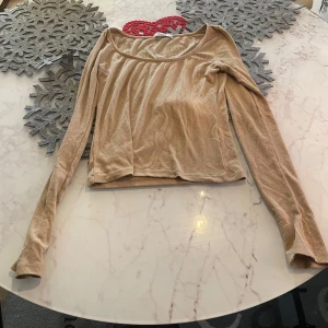 Beige ribbad topp från NA-KD - Snygg beige ribbad topp från NA-KD med långa ärmar. Perfekt för en stilren look. Tillverkad i Turkiet.