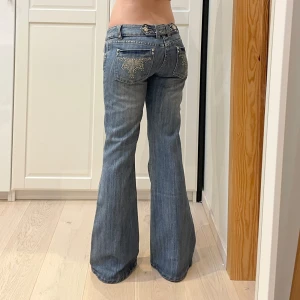 Lågmidjade bootcut jeans🤩 - Rhinestones och massa snygga detaljer💕midja 41 cm rakt över plus stretch, gren 20 cm o innerben 80 cm🫶🏻Jae 169 o xs-s o håller in i midjan på bilderna. Märkta storlek 12 men uppskattar till M, mer åt S än L