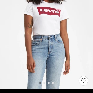 Vit t-shirt från Levi's - Vit t-shirt från Levi's med det klassiska röda logotyptrycket på bröstet. Kortärmad och i bomull, perfekt för en avslappnad stil. Säljer T-shirten för 100kr. Pris kan diskuteras vid snabbaffär🥰