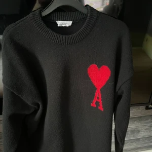 Ami Alexandre Mattiussi - Snygg svart tröja från Ami Alexandre Mattiussi med ett rött hjärta och bokstaven 'A' på bröstet. Använd några gånger men ändå som ny i skicket. Storlek M men passar S. Vet ej om den  är äkta eller inte men kan ej bevisa det därför priset