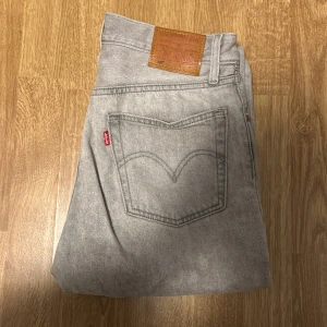 Grå Levis jeans - I princip sprillans nya snygga grå Levis jeans med klassisk design och rak passform. De har en låg midja och är tillverkade i slitstarkt denim. Perfekta för en avslappnad stil.